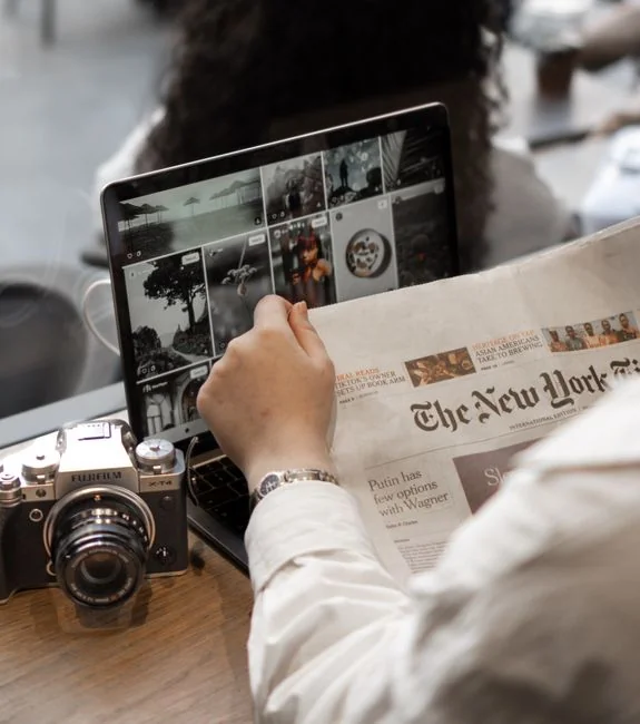 Person analyzes stock data with a smartphone and laptop, indoors.